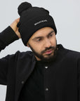 Unisex Signature pom pom knit beanie in black with embroidered WHATEVR text, front view