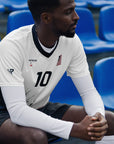 Man wearing a sports jersey with number 10 sitting on blue chairs.