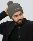 Unisex Signature pom pom knit beanie in gray with embroidered WHATEVR text, front view
