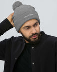 Unisex Signature pom pom knit beanie in gray with embroidered WHATEVR text, front view