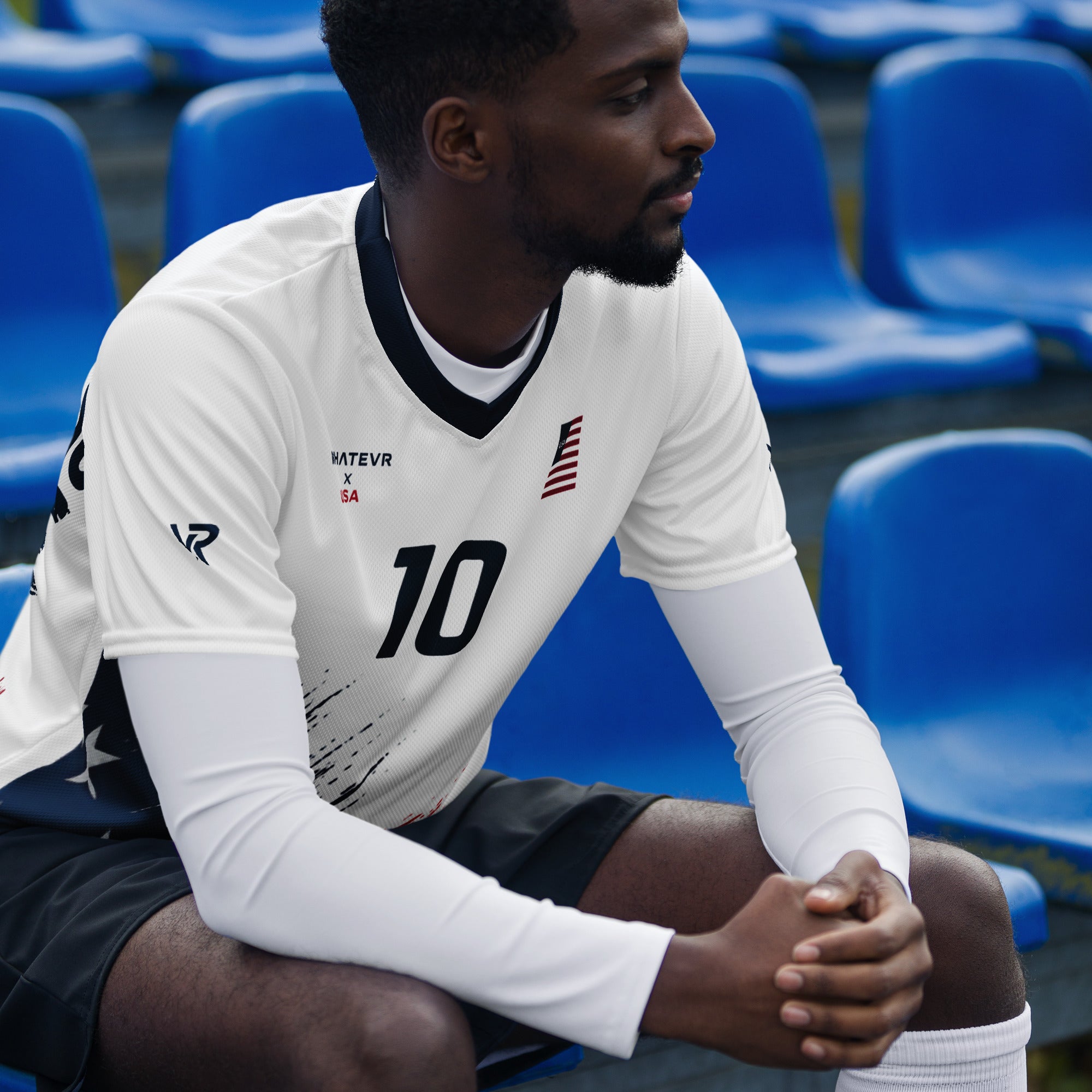 Man wearing a sports jersey with number 10 sitting on blue chairs.