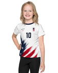 Child wearing a white sports jersey with red, white, and blue design on a white background