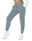 Women's essential relaxed sweatpants in blue with embroidered detailing, front view.